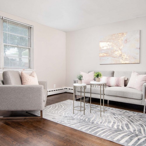 Spacious and well lit living room with wood floors and an open floor plan with access to the kitchen.